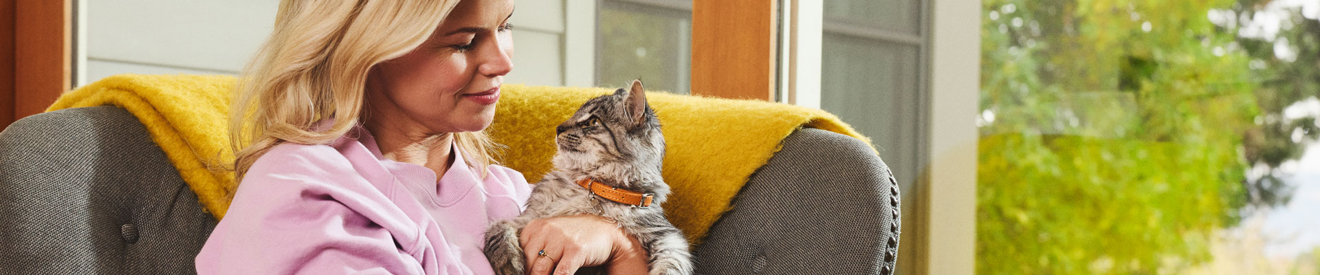 A woman sits in a chair and holds her kitten