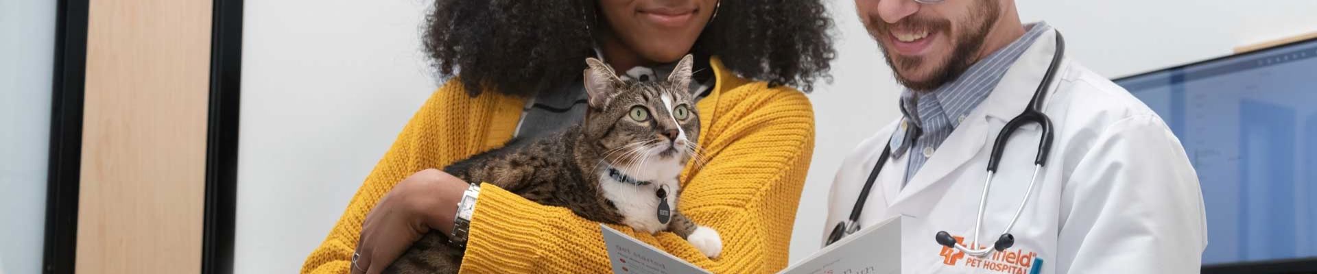 A woman holding her cat talks to a Banfield veterinary professional