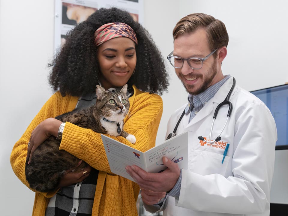 A Banfield veterinary professional talking to a pet owner holding her cat