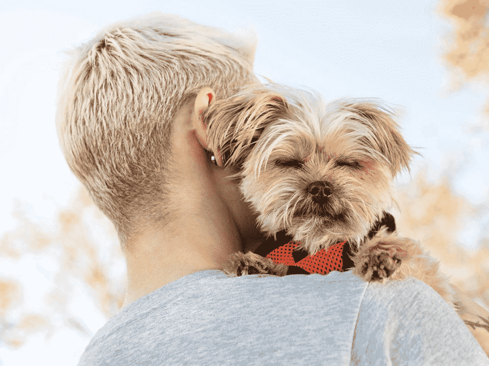 A woman with a puppy on her shoulders